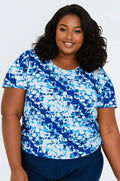 Woman wearing a blue and white patterned shirt against a plain background