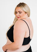 Woman wearing a black bra against a white background