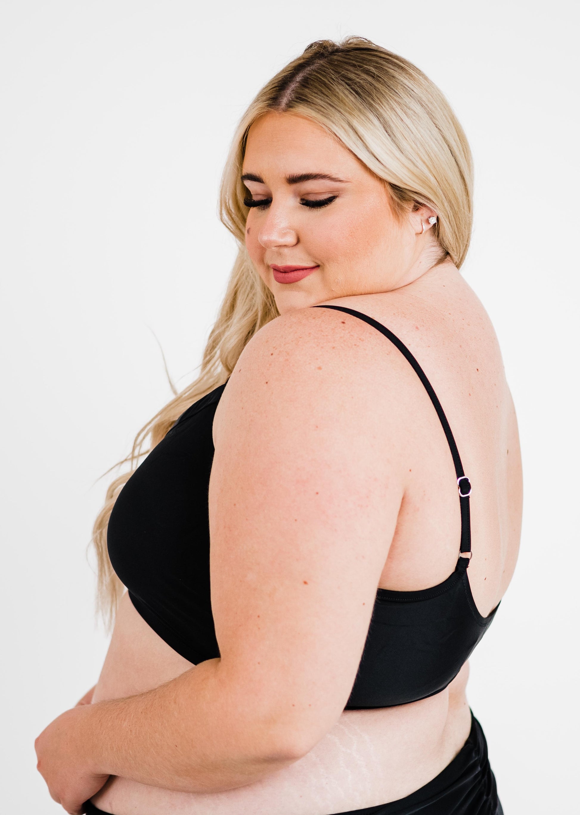 Woman wearing a black bra against a white background