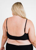 Person wearing a black bra against a white background