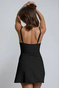 A woman wearing a black dress with her hands raised, back view.
