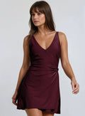 A woman wearing a green sleeveless swim dress with a v-neckline and decorative side tie, designed for plus-size with hidden bikini bottoms.