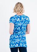 Woman wearing a blue and white floral tunic against a white background