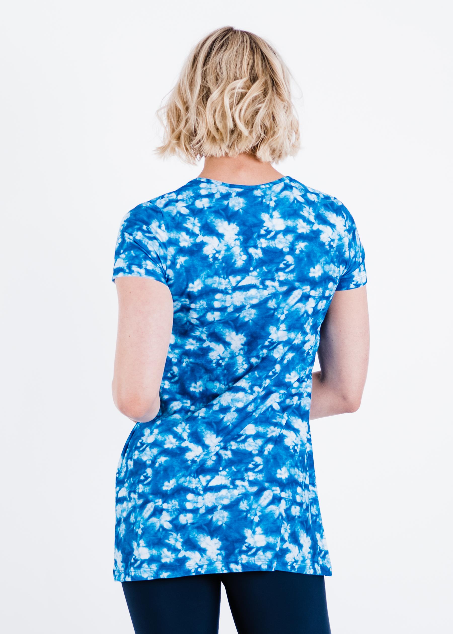 Woman wearing a blue and white floral tunic against a white background