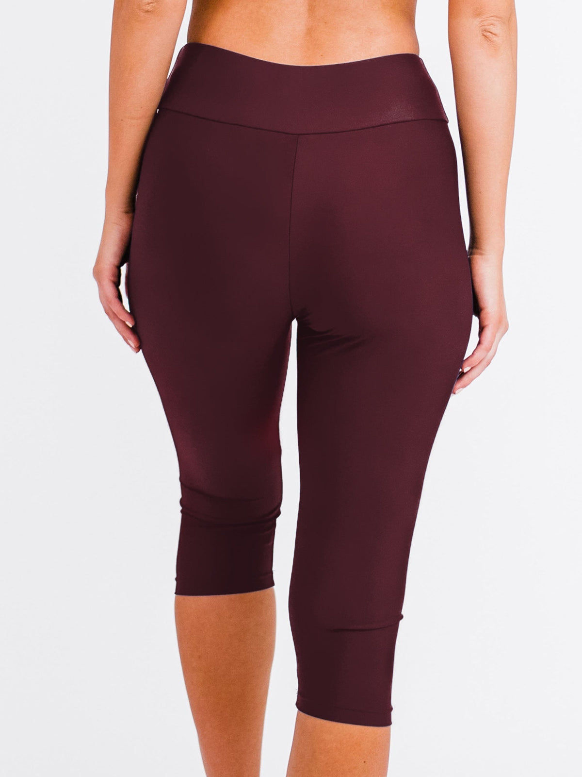 Wine Capri swim leggings worn by a person on a white background