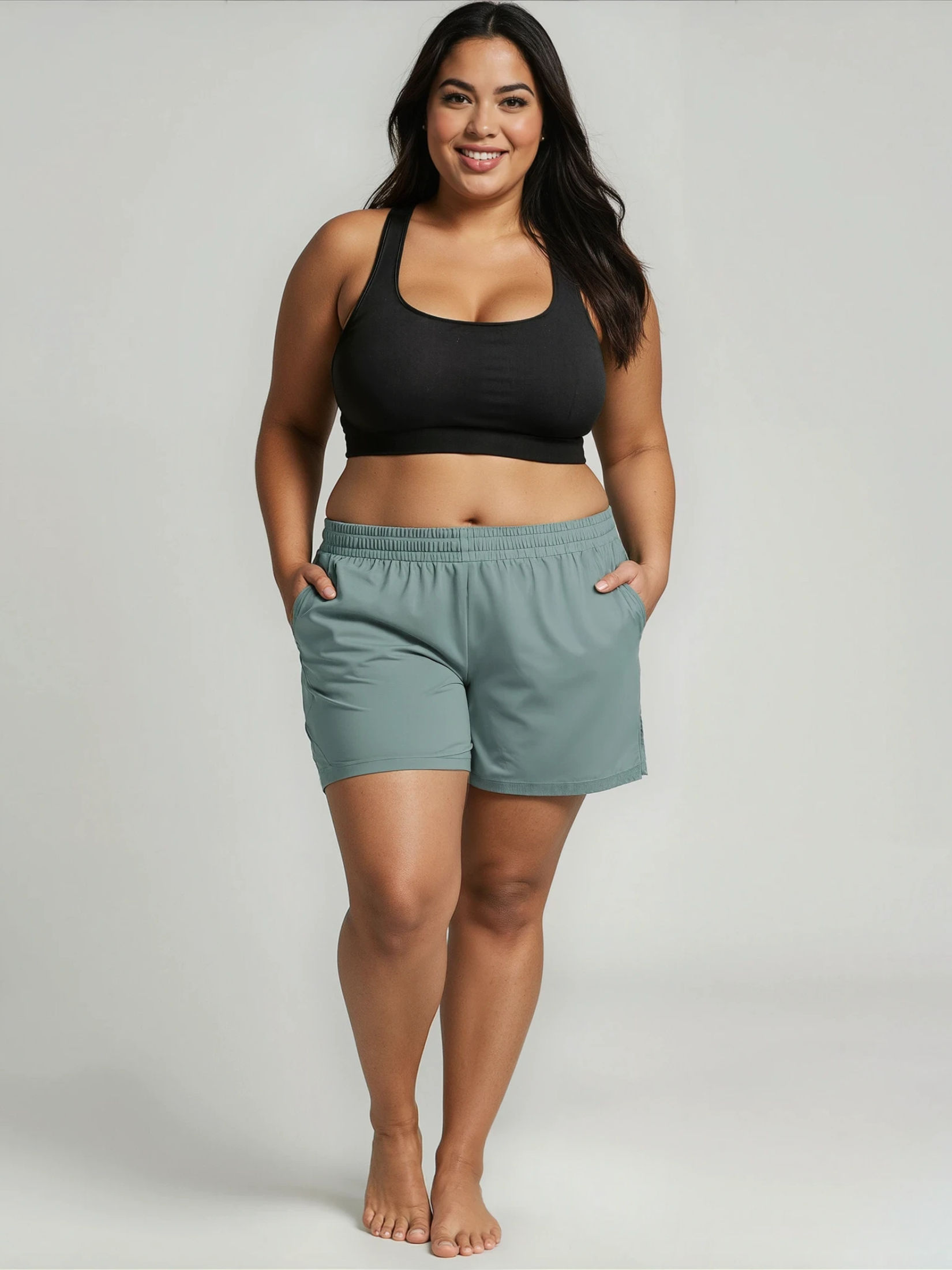 Woman wearing a black sports bra and light green shorts on a plain background