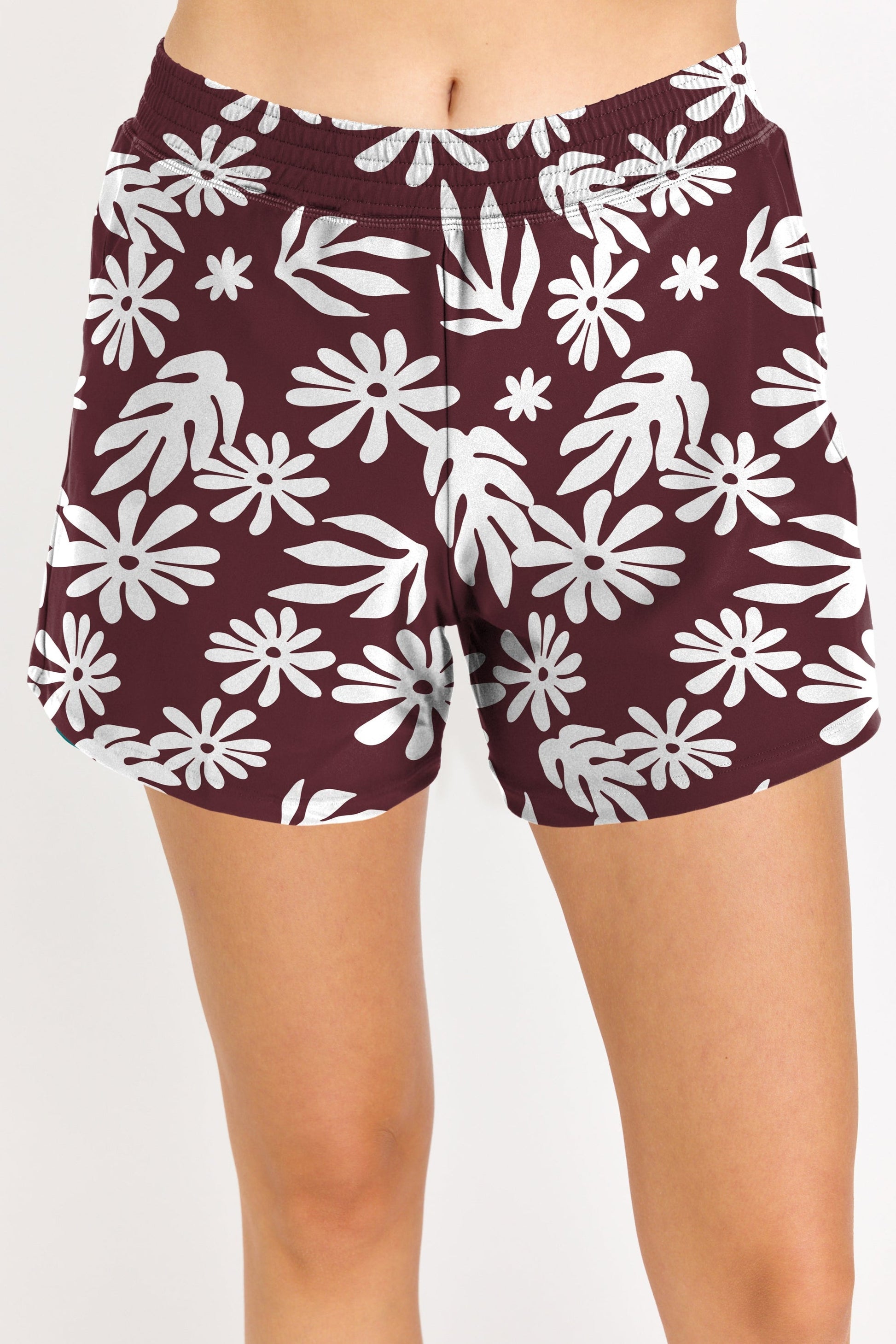 Maroon shorts with white floral pattern worn by a person on a plain background