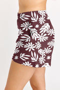 Maroon skirt with white floral pattern worn by a person on a plain background