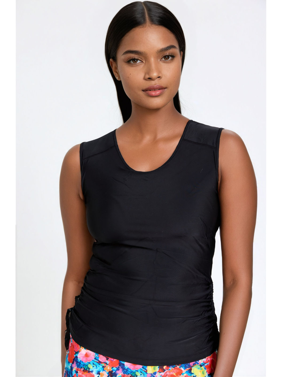 Woman wearing a black sleeveless top with colorful pants on a white background