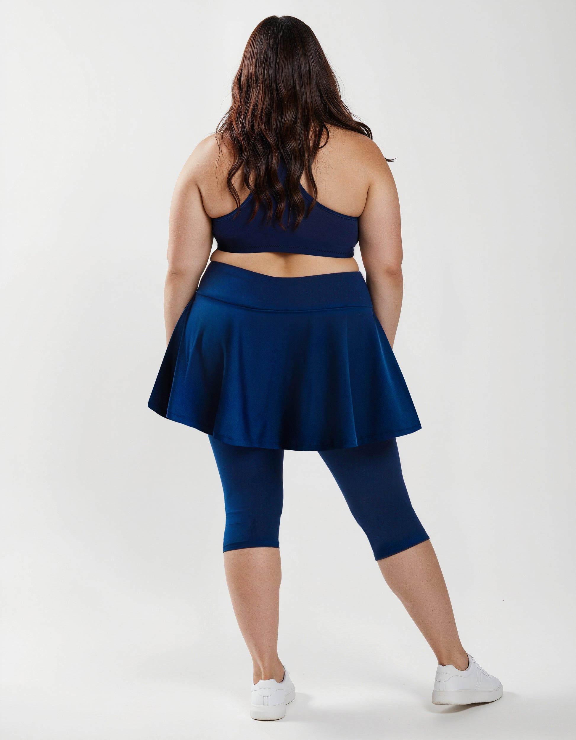 Flared Swim Skort With Capri Leggings | Plus Size shown from the back on a model in navy blue modest swimwear with a supportive fit for every body