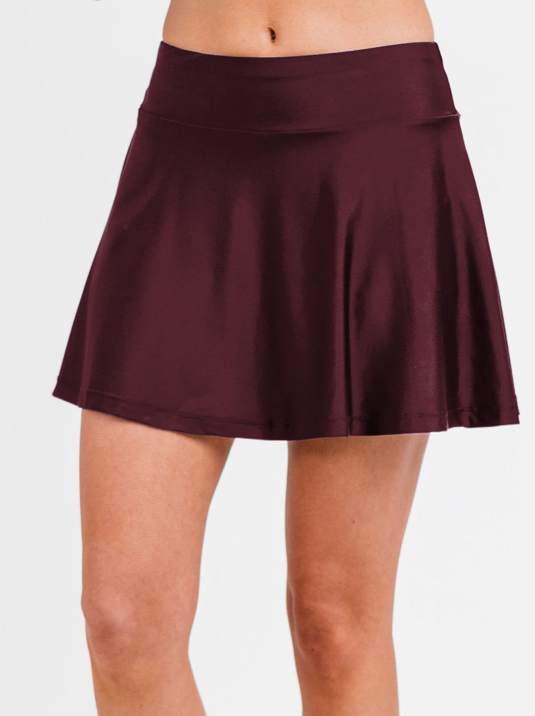 Woman wearing a Flowy Swim Skort With Shorts in navy and white stripes standing on a wooden patio holding a camera, highlighting size-inclusive, modest, supportive swimwear with a comfortable fit. Swimwear designed for every body.