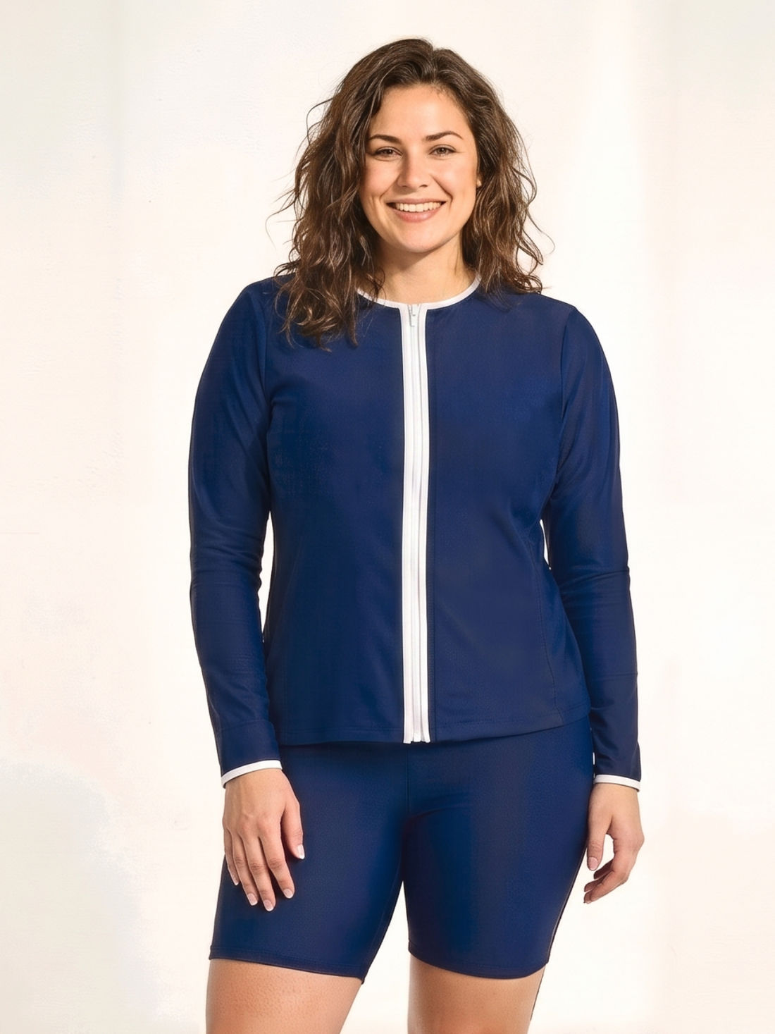 Full-Zip Peyton Two-Toned Swim Top | Plus Size shown on a woman walking along the beach in black supportive swimwear with modest coverage and a comfortable fit