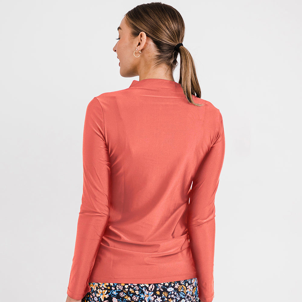 Smiling woman wearing a rust-colored Half-Zip Nora Swim Top | Final Sale with long sleeves and a front zipper, styled with floral swim bottoms, showcasing size-inclusive, modest, supportive swimwear designed for every body with a comfortable fit.