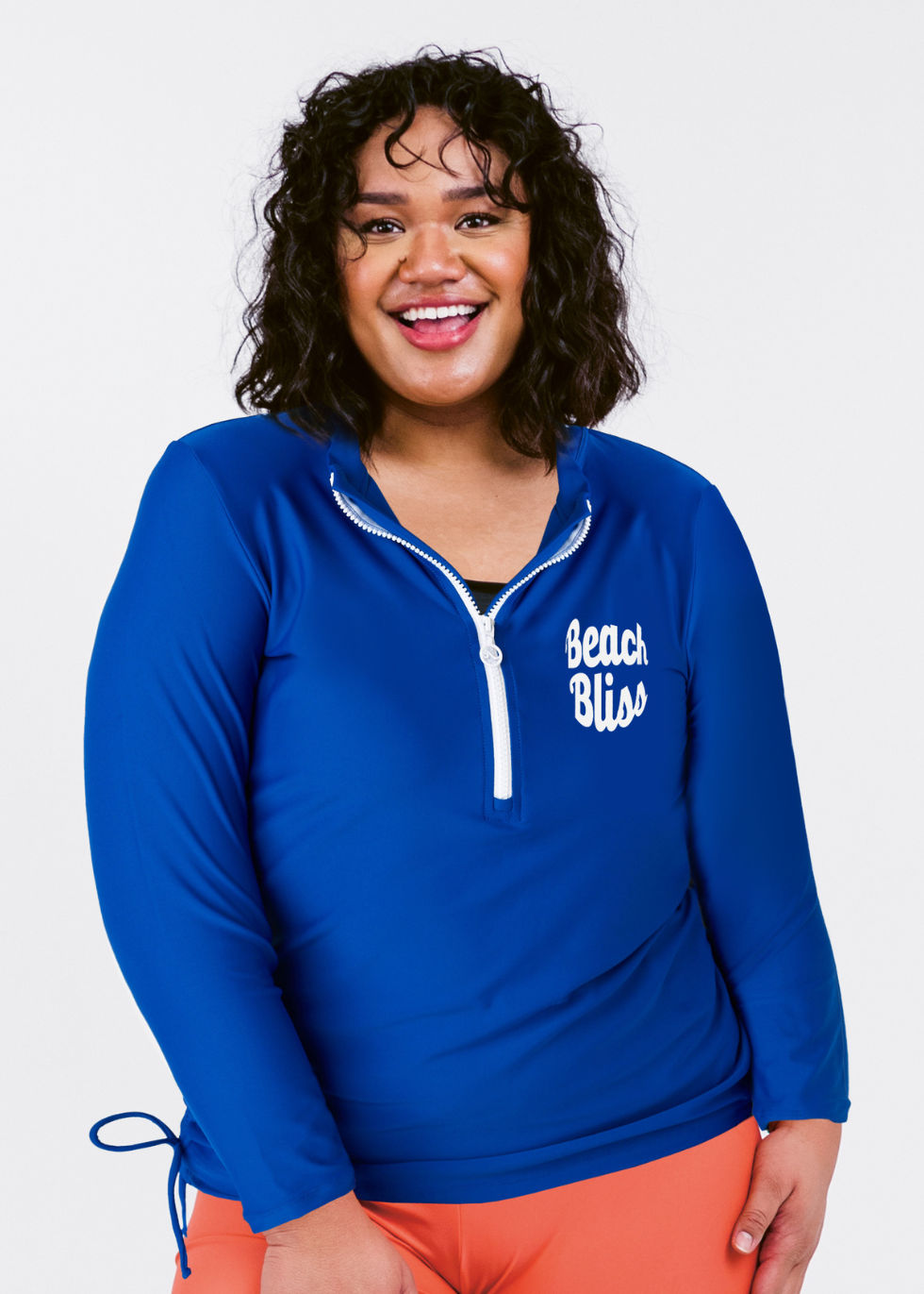 Woman wearing a blue 'Beach Bliss' shirt with orange pants on a white background