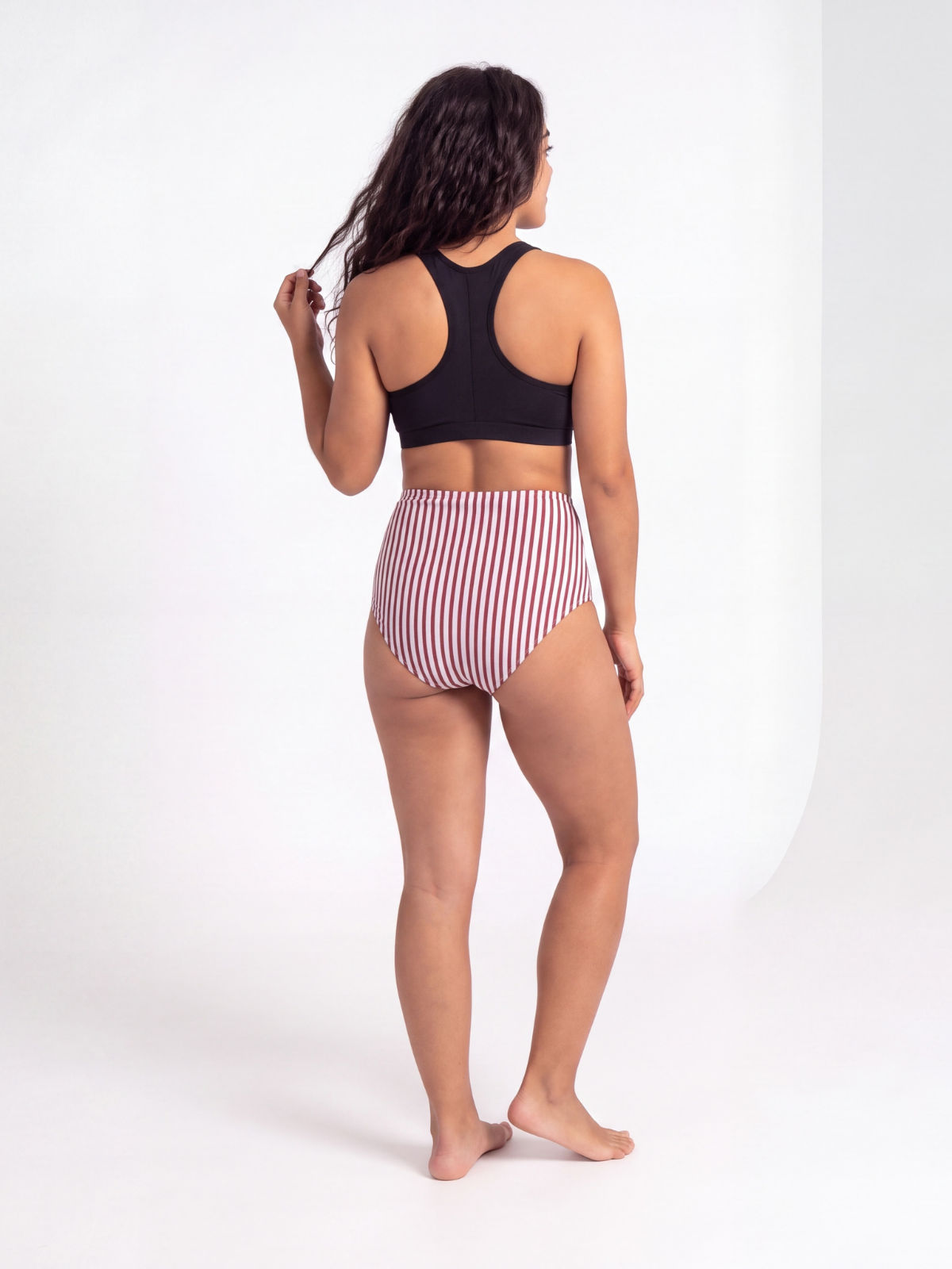 High Waisted Full Coverage Bikini Bottom in red and white stripes modeled from the back with a high rise fit and comfortable coverage for modest swimwear designed for every body