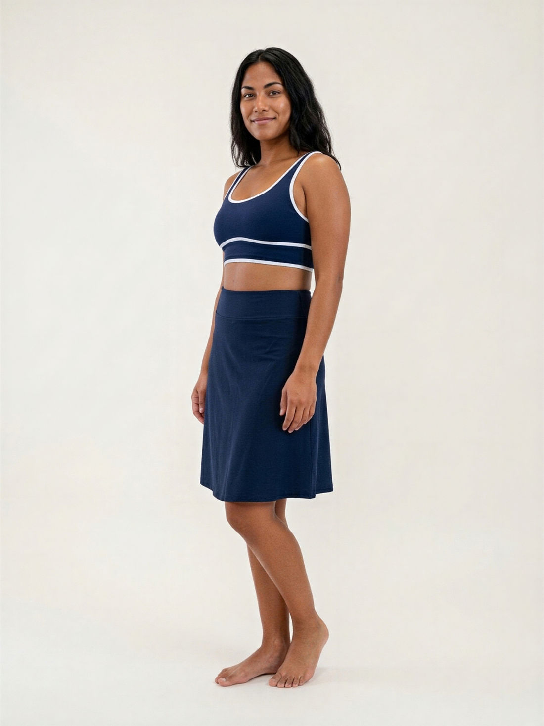 Knee Length Swim Skort With Bike Shorts modeled on a smiling woman wearing a patterned swim top and black skort for modest supportive size inclusive swimwear