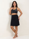 Knee Length Swim Skort With Bike Shorts modeled on a smiling woman wearing a patterned swim top and black skort for modest supportive size inclusive swimwear