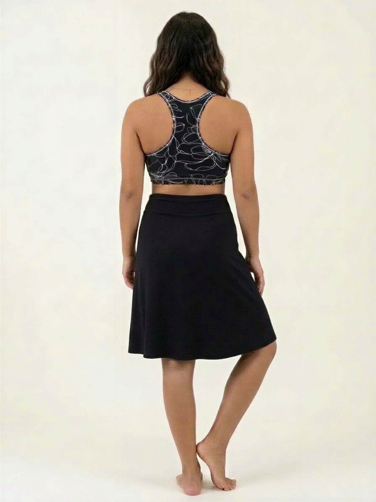 Knee Length Swim Skort With Bike Shorts shown from the back with a black knee length skirt and supportive size inclusive swimwear designed for every body