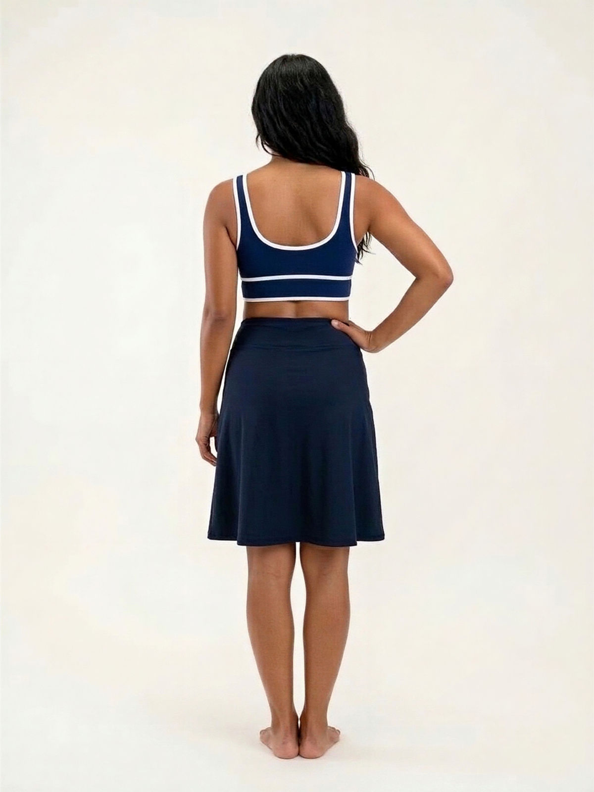 Knee Length Swim Skort With Bike Shorts shown from the back on a woman in navy swimwear with a knee length skirt and built in shorts for a comfortable fit