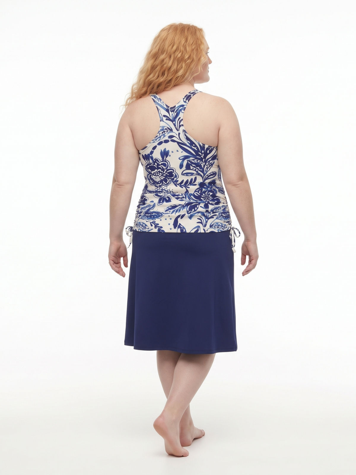 Back view of a woman wearing Long Swim Skort With Capri Leggings | Plus Size navy floral swimwear with a modest comfortable fit for every body