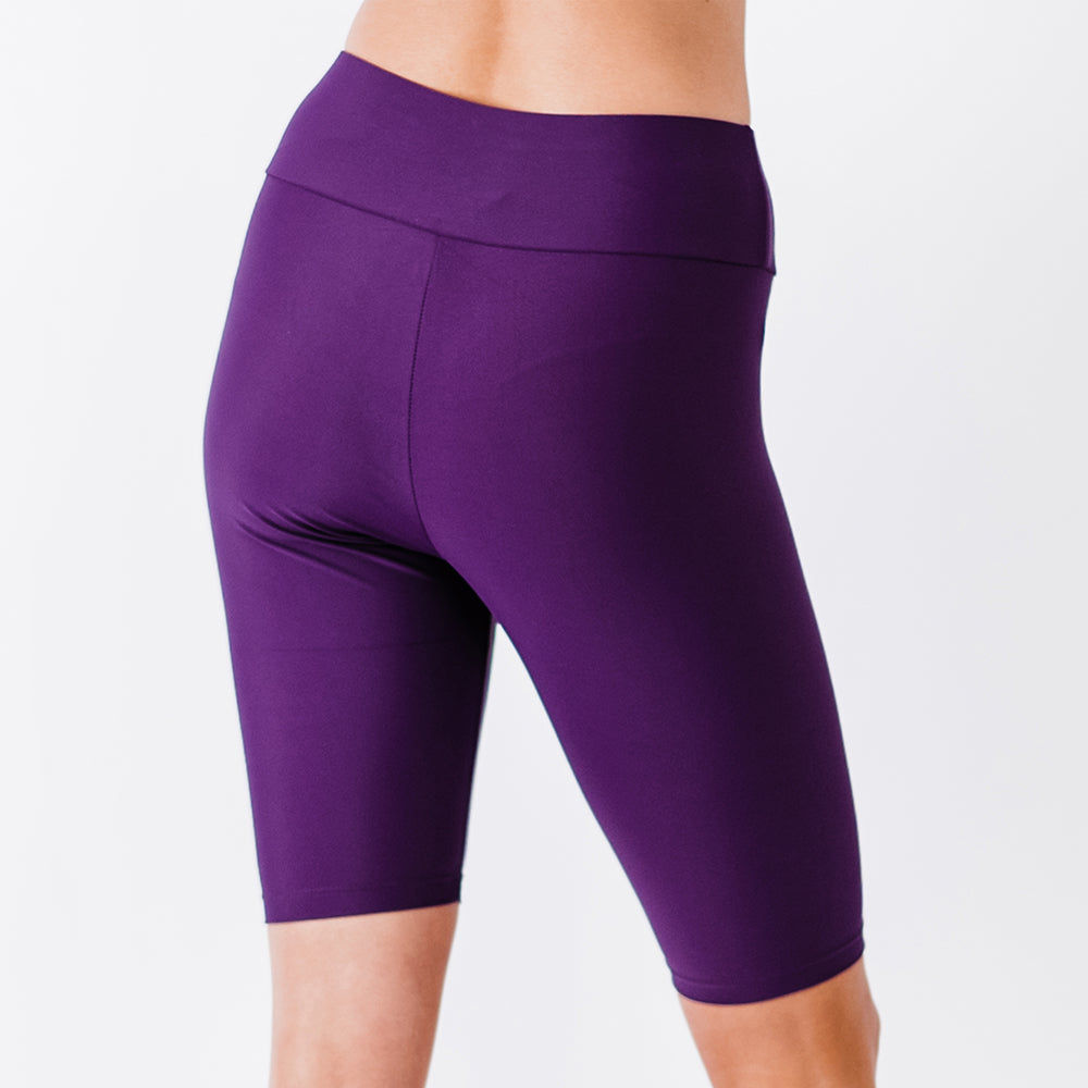 Back view of a model wearing Long Bike Swim Shorts in a deep eggplant purple color, showcasing size-inclusive, modest, supportive swimwear with a comfortable fit, swimwear designed for every body.