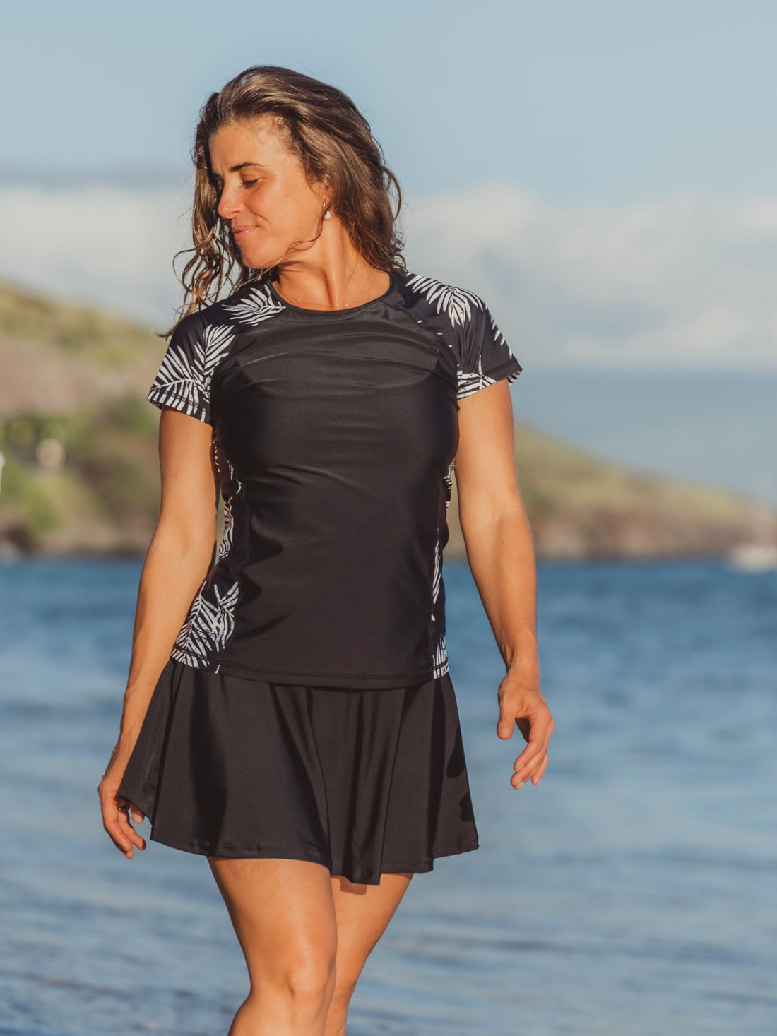 Model wearing Loose Fit Adele Swim Top with striped short sleeves and side panels over black swim shorts showcasing size inclusive supportive swimwear for every body