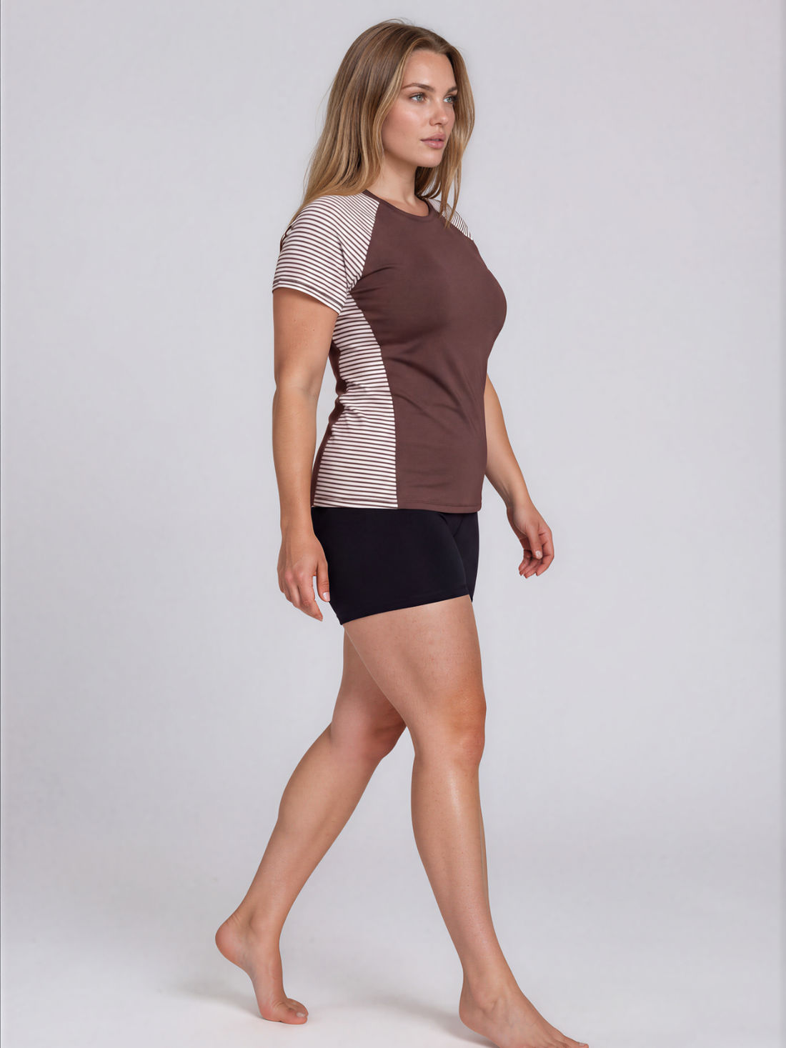 Model wearing Loose Fit Adele Swim Top with striped short sleeves and side panels over black swim shorts showcasing size inclusive supportive swimwear for every body