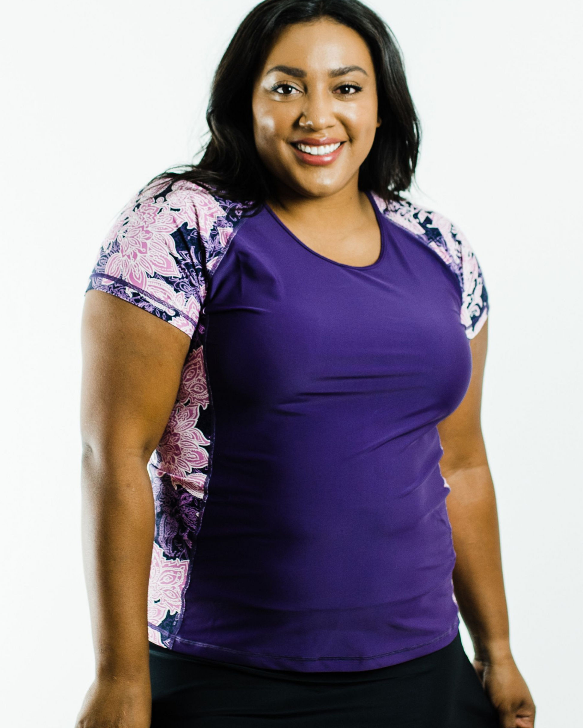 Woman wearing a purple top with floral sleeves on a white background