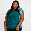 Plus size woman wearing the Loose Fit Adele Swim Top | Final Sale in a dark jade color with floral side panels, showcasing size-inclusive, modest, and supportive swimwear designed for every body.