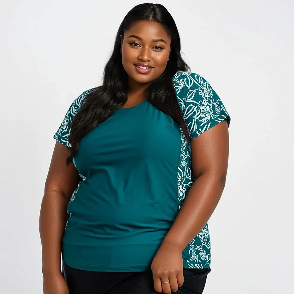 Plus size woman wearing the Loose Fit Adele Swim Top | Final Sale in a dark jade color with floral side panels, showcasing size-inclusive, modest, and supportive swimwear designed for every body.