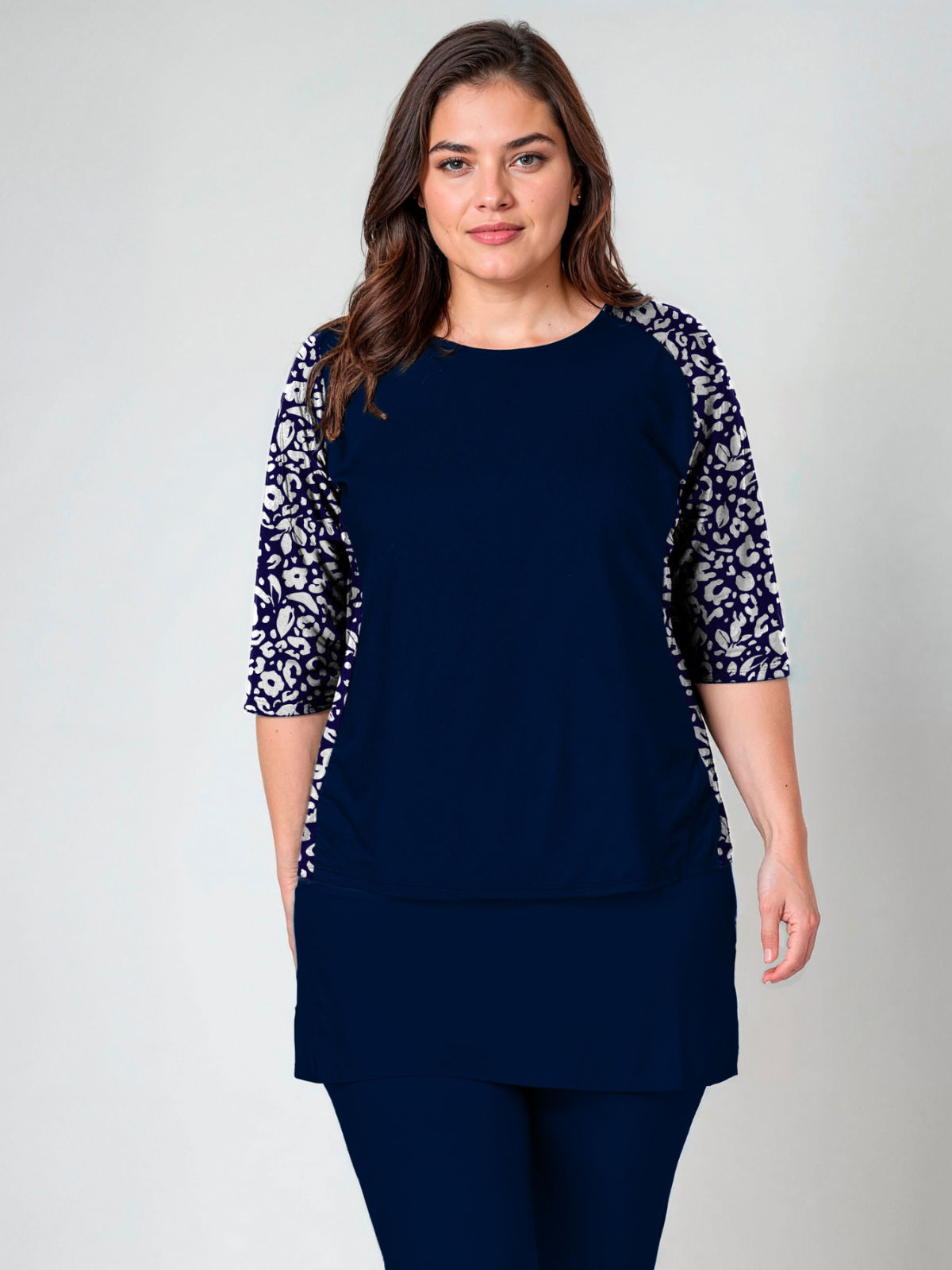 Woman wearing a navy blue outfit with floral sleeves on a plain background