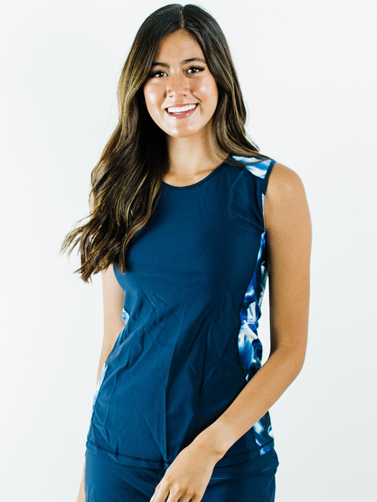 Woman wearing a blue sleeveless top with a floral pattern on a white background