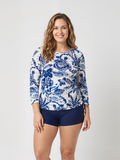 Margaux Swim Top | Plus Size on a smiling woman wearing a blue and white floral top with long sleeves and navy swim shorts for comfortable size inclusive swimwear
