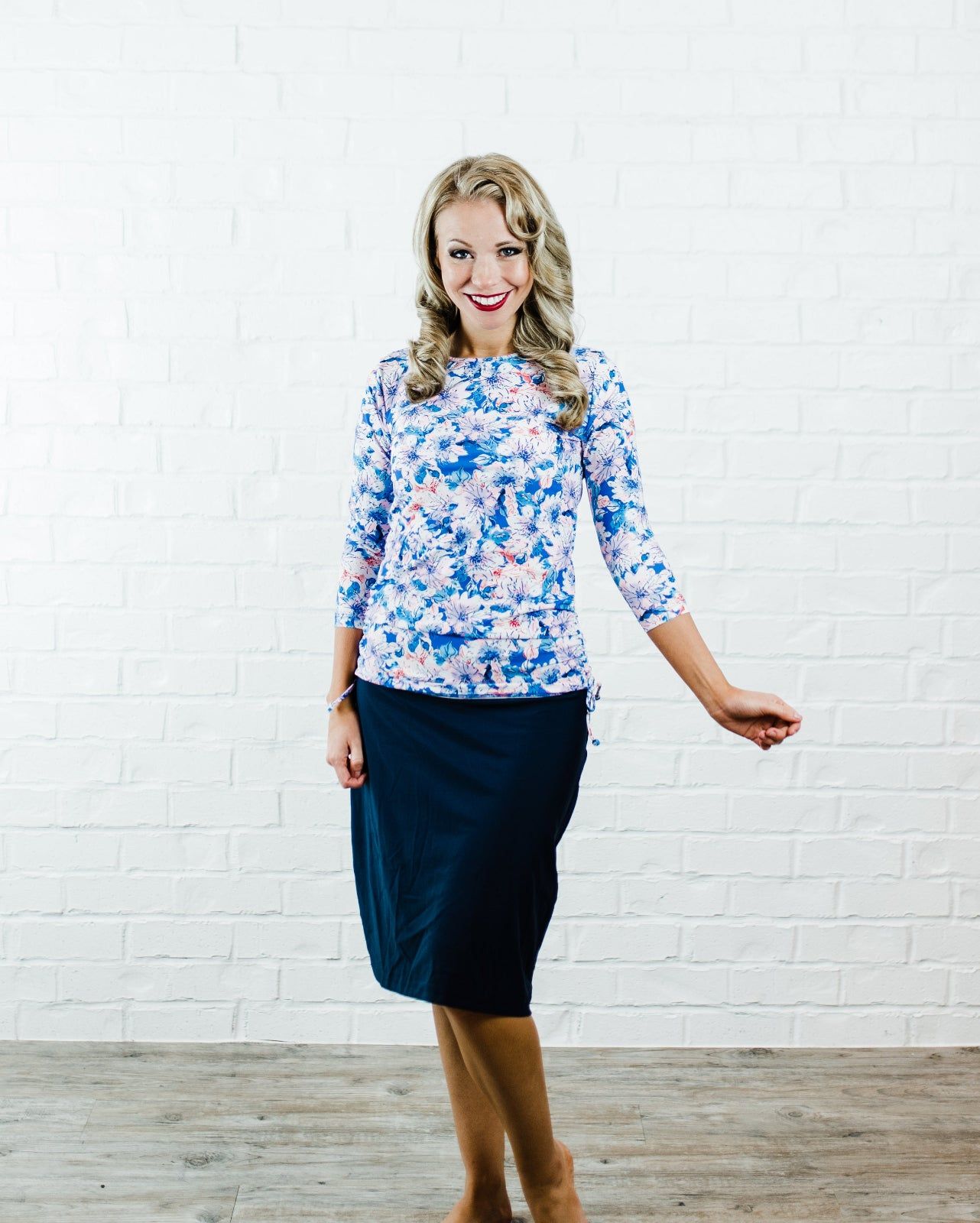 Smiling woman wearing Margaux Swim Top | Final Sale with watercolor floral print and three-quarter sleeves paired with a modest dark skirt, showcasing swimwear designed for every body.