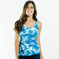 Woman wearing a blue patterned swim top smiling confidently showcasing the Maya Tankini Swim Top With Removable Cups | Final Sale, designed for a comfortable and supportive fit.