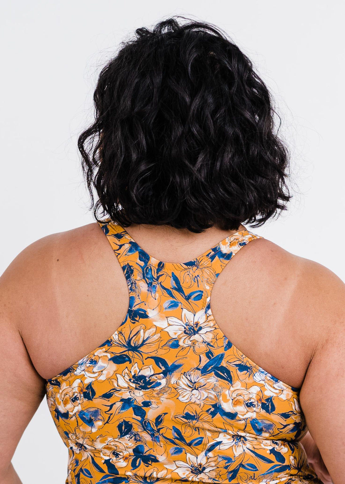 Person wearing a yellow floral dress with a white background