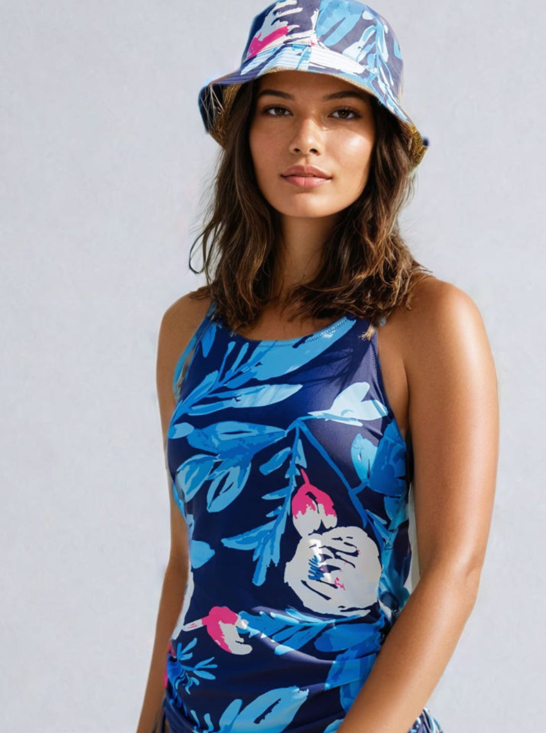Woman wearing Maya Tankini Swim Top With Removable Cups in a stylish black and white floral design, accessorized with a sun hat and beach bag, exemplifying supportive swimwear with a comfortable fit. Swimwear designed for every body.