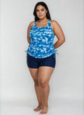 A woman modeling a blue and white tie-dye halter tank top with matching navy blue swim shorts against a light gray studio background.