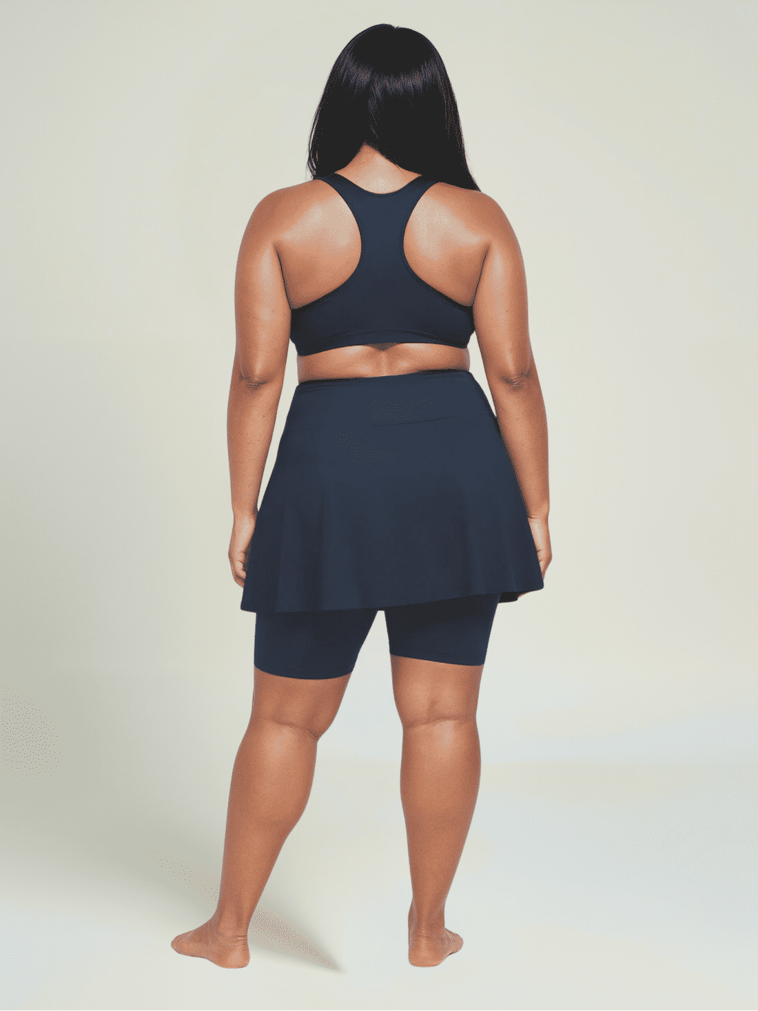 Woman wearing a navy blue athletic outfit on a plain background