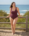 Mila One-Piece Swimsuit | Plus Size in burgundy, modeled by a smiling woman on a sandy beach, showcasing size-inclusive, modest, supportive swimwear with a comfortable fit