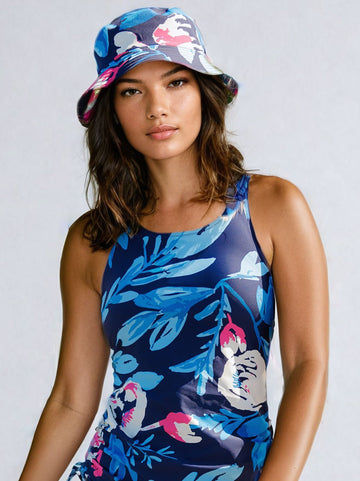 Woman wearing a floral bucket hat and matching blue floral swimwear, showcasing a comfortable fit with supportive and size-inclusive style. Swimwear designed for every body.