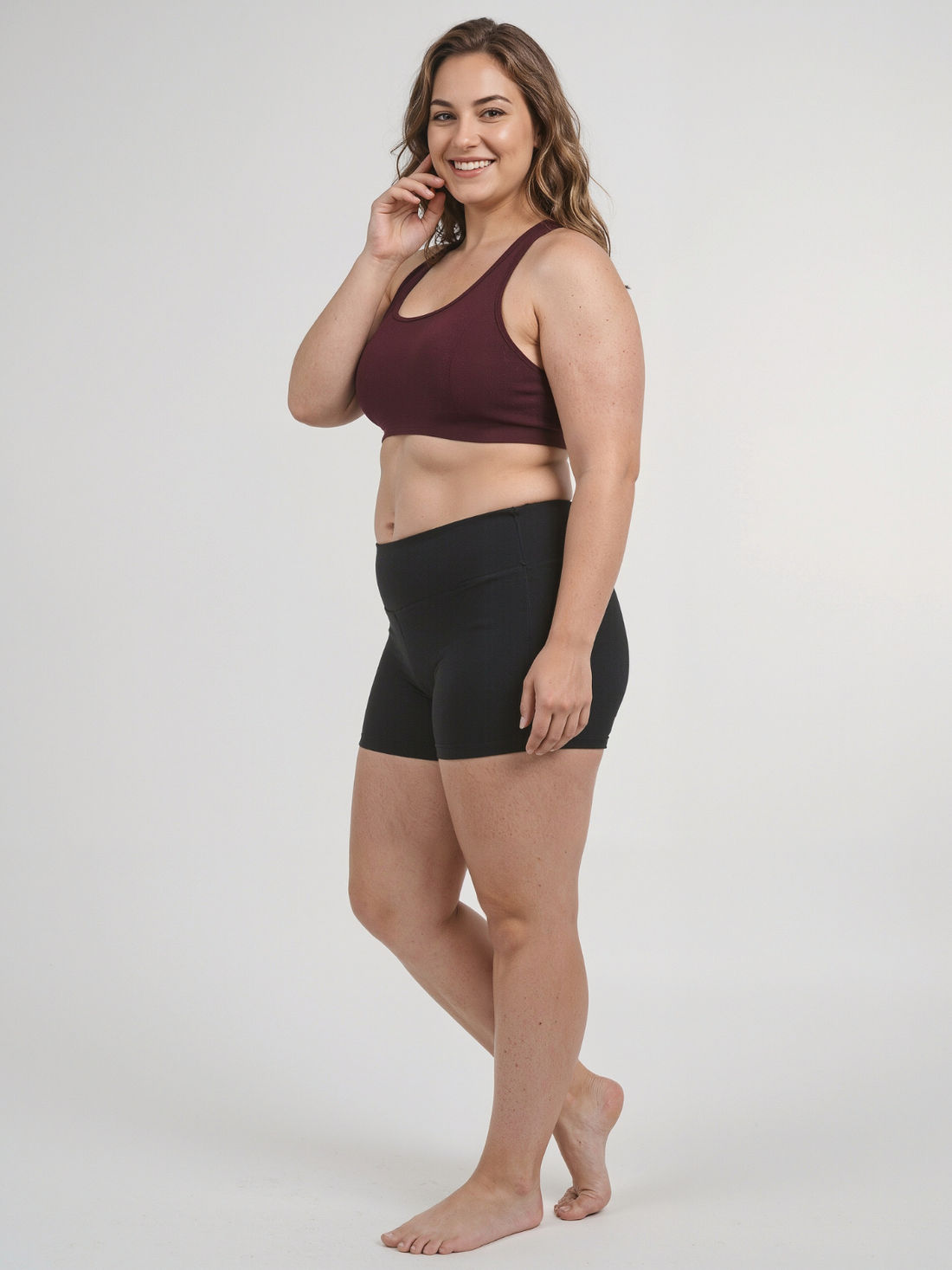 Woman wearing a patterned Racerback Swim Bra | Plus Size standing on the beach with arms raised, showcasing size-inclusive, supportive swimwear designed for every body.