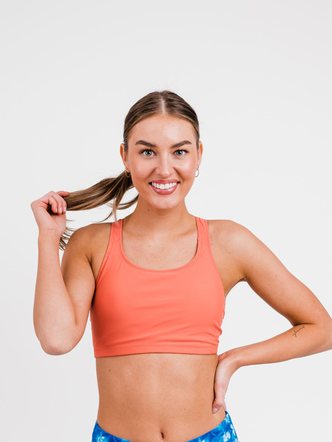Woman wearing a pink sports bra with a white pattern on a white background