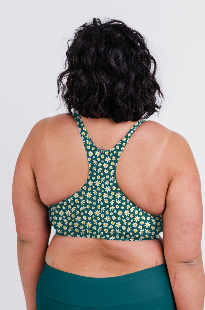 Person wearing a green floral sports bra and leggings on a white background