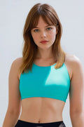 Woman wearing a turquoise sports bra against a plain background