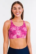 Woman wearing a pink sports bra with a white pattern on a white background