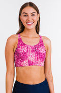 Woman wearing a pink sports bra with a white pattern on a white background