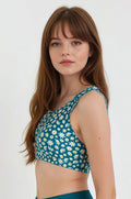 Woman wearing a green floral bikini top against a white background