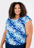 Woman wearing a blue and white floral top against a plain background