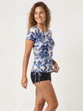 Woman wearing the Short Sleeve Adele Swim Top in a blue floral print with black swim shorts for supportive comfortable swimwear designed for every body